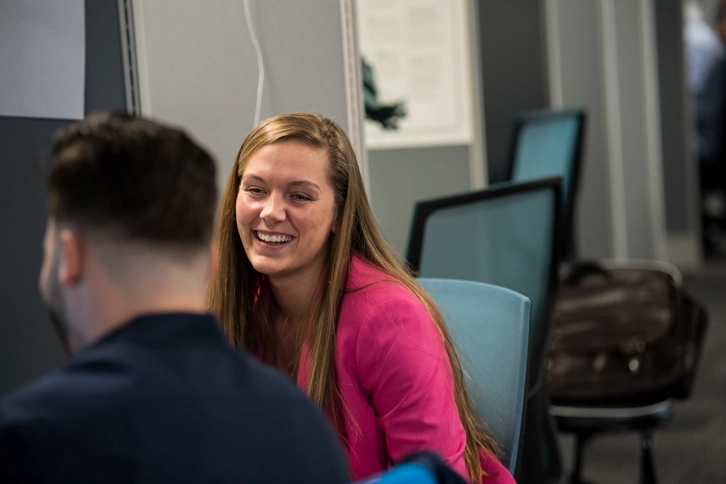 Lady Wearing Pink Working Alongside A Male Colleague In An Office
