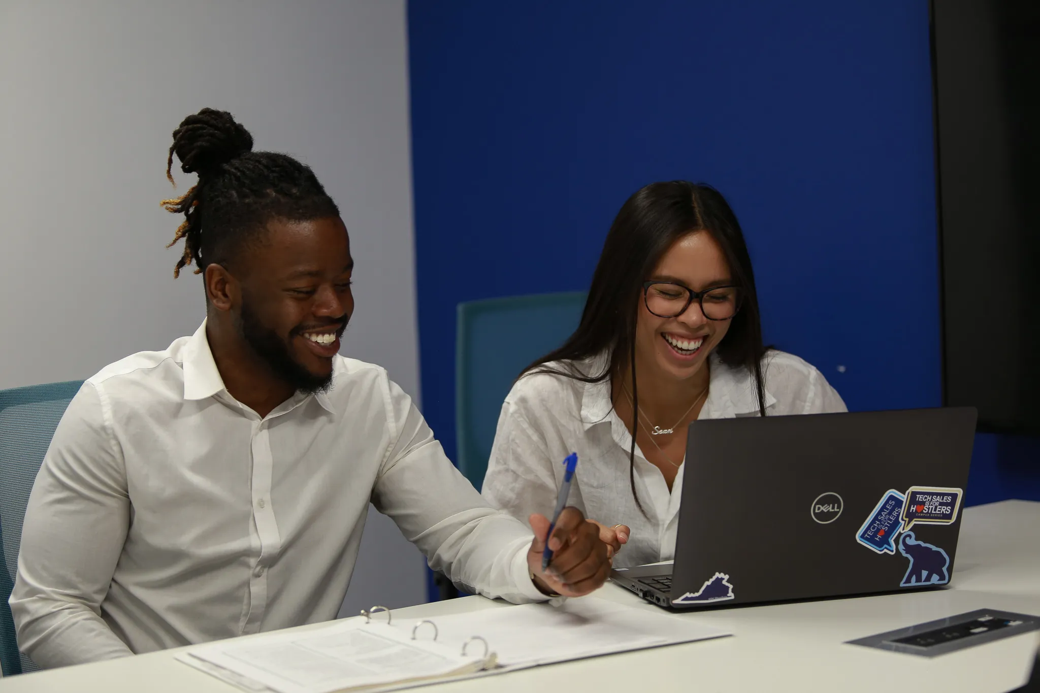 Two People Working At A Laptop Blue Background